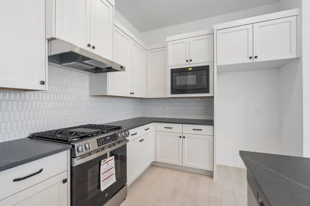 a kitchen with granite countertop white cabinets and stainless steel appliances