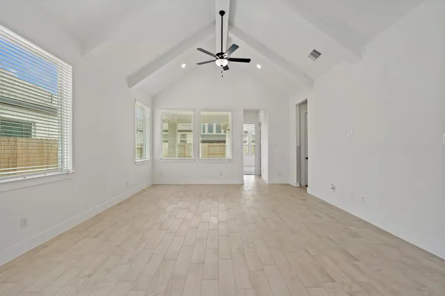 an empty room with windows and ceiling fan