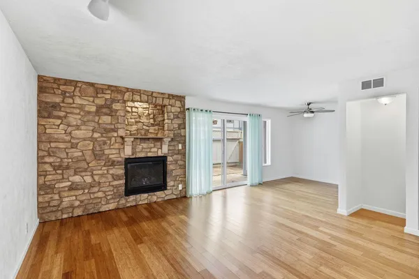 an empty room with wooden floor and a ceiling fan