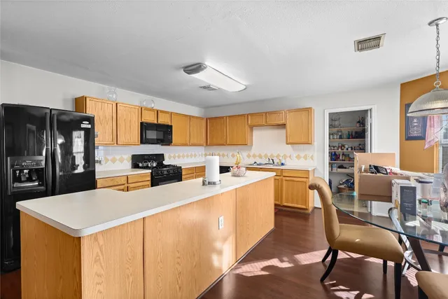 a large kitchen with a table chairs microwave and refrigerator