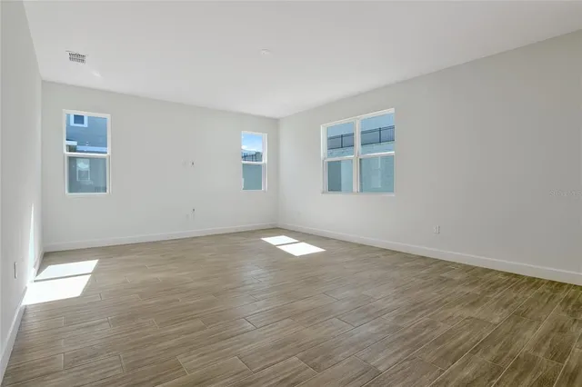 an empty room with wooden floor and windows