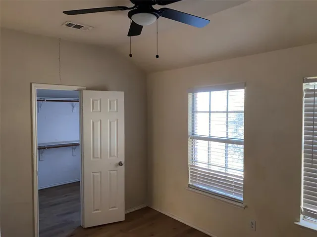 a view of empty room with wooden floor and fan