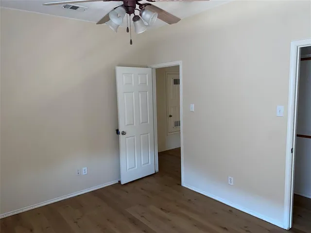 an empty room with a hardwood and ceiling fan