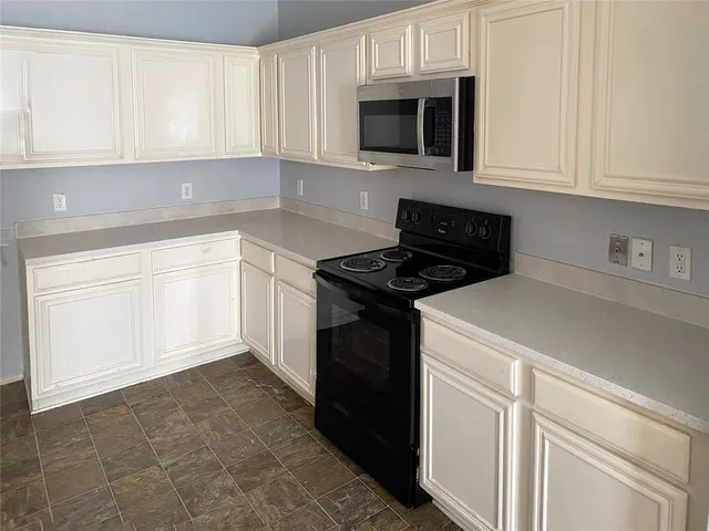 a kitchen with granite countertop white cabinets and stainless steel appliances