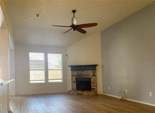 an empty room with wooden floor fireplace and windows
