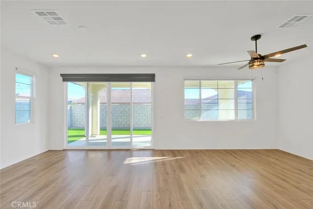 an empty room with windows and fan