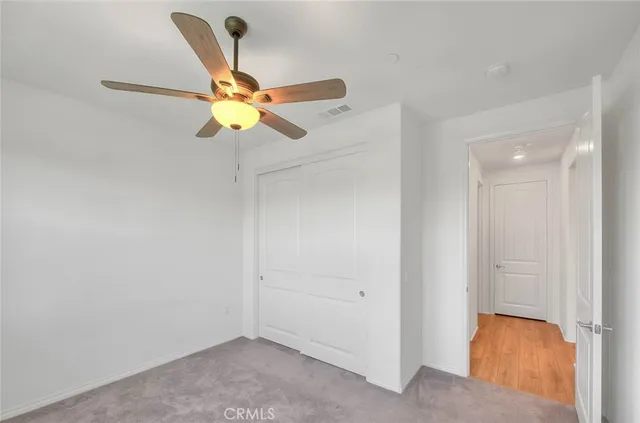 an empty room with window and chandelier fan