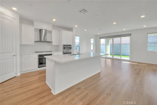 a large kitchen with stainless steel appliances granite countertop a large counter top a stove and a wooden floors