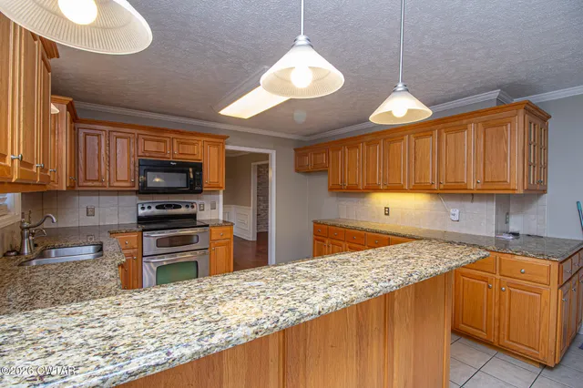 a kitchen with stainless steel appliances granite countertop a stove a sink dishwasher and a refrigerator with wooden cabinets