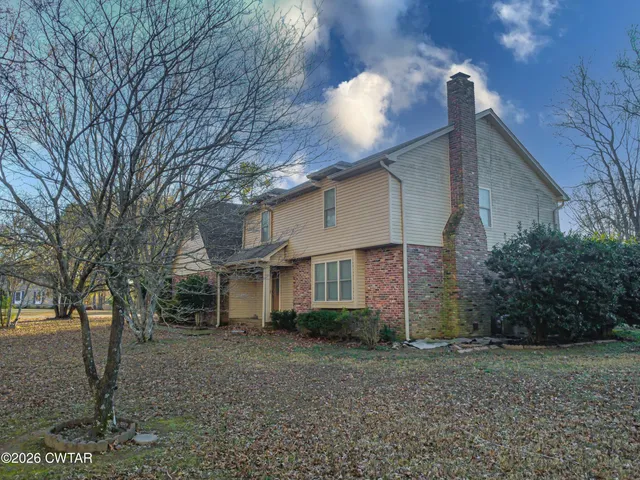 a view of an empty room with wooden floor fireplace and a window
