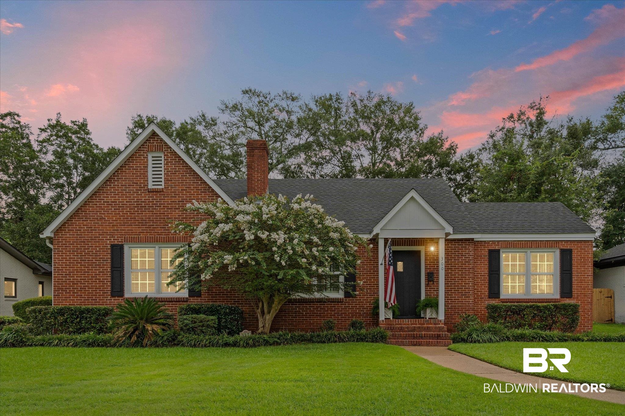 300 Woodlands Avenue Mobile, AL 36607 - Photo 1 of 23 View of front facade featuring a front yard, a chimney, brick siding, and roof with shingles