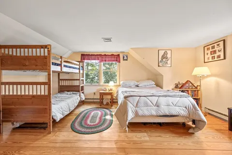 a bedroom with a bed wooden floor and window