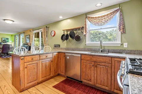 a kitchen with stainless steel appliances granite countertop wooden cabinets a sink and a large window