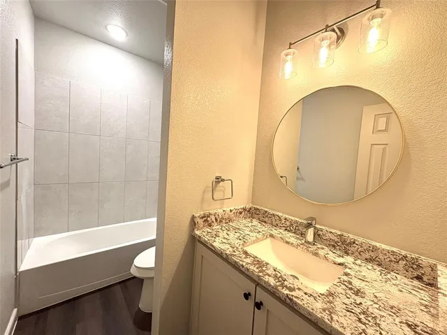 a bathroom with a granite countertop sink mirror vanity and toilet