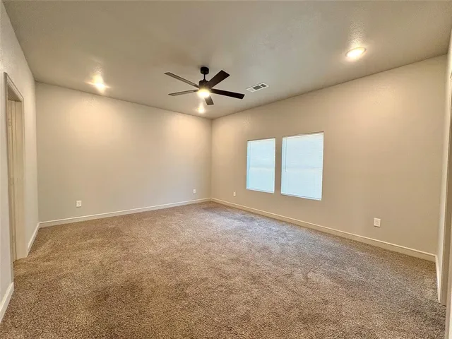 an empty room with a ceiling fan and window