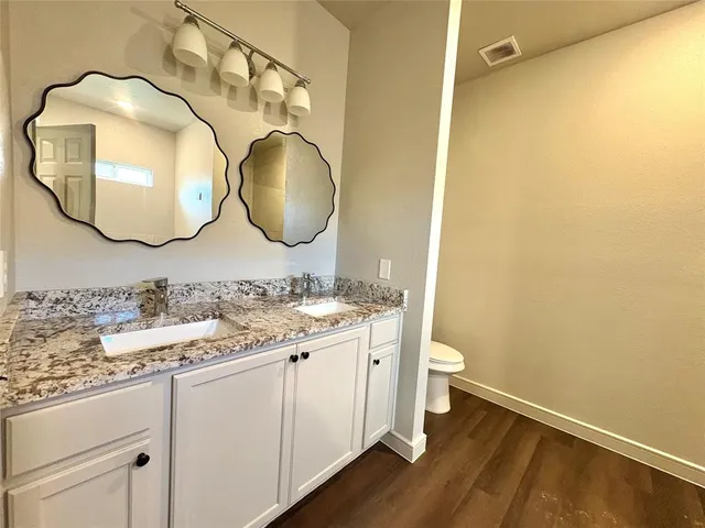 a bathroom with a granite countertop toilet sink and mirror