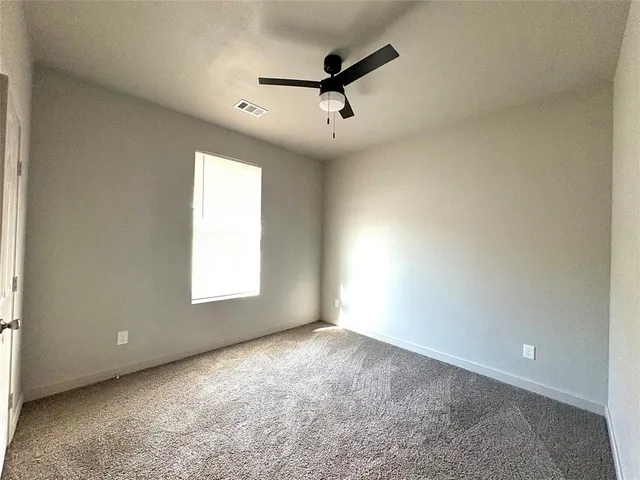 en empty room with windows and ceiling fan
