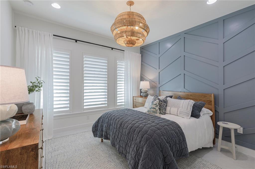 8963 Gustavia Court Naples, FL 34113 - Photo 24 of 47 a bedroom with a bed and a chandelier