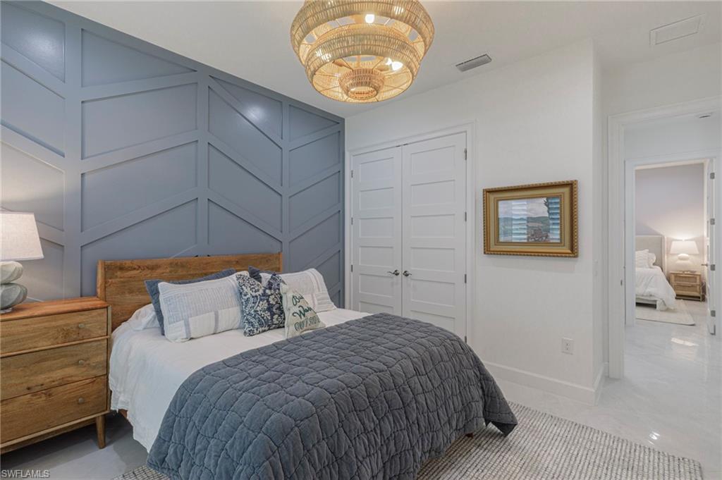 8963 Gustavia Court Naples, FL 34113 - Photo 25 of 47 a bedroom with a bed and a lamp on dresser