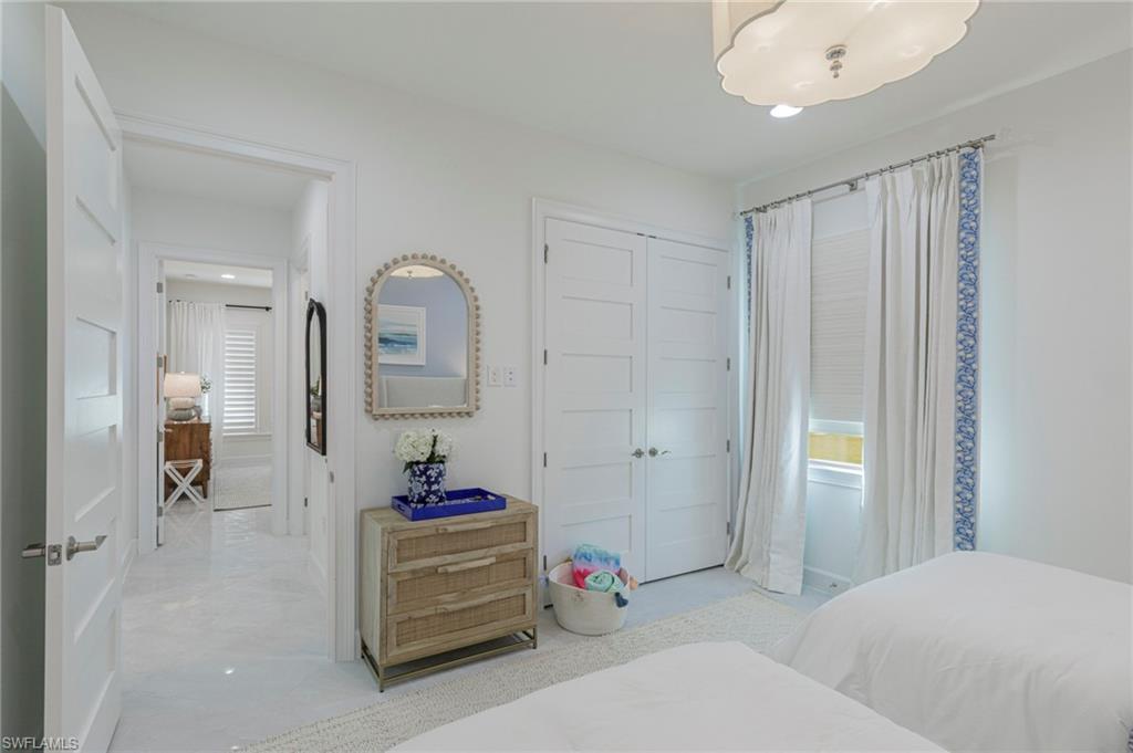 8963 Gustavia Court Naples, FL 34113 - Photo 28 of 47 a bedroom with a bed and a mirror