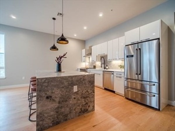 243 Condor Street, Unit 3 Boston, MA 02128 - Photo 3 of 16 a kitchen with kitchen island white cabinets and stainless steel appliances