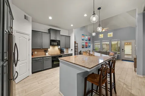 a kitchen with kitchen island granite countertop a sink a center island and stainless steel appliances