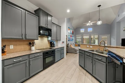 a kitchen with stainless steel appliances granite countertop a sink a stove top oven a counter space and cabinets