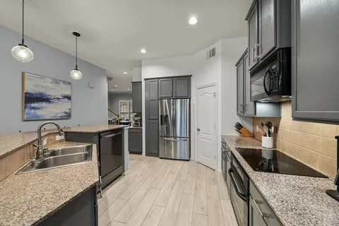 a kitchen with granite countertop a sink a counter top space stainless steel appliances and cabinets