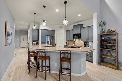 a kitchen with kitchen island a dining table chairs sink and wooden floor