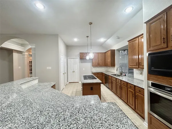 a large kitchen with stainless steel appliances kitchen island granite countertop a stove and a sink