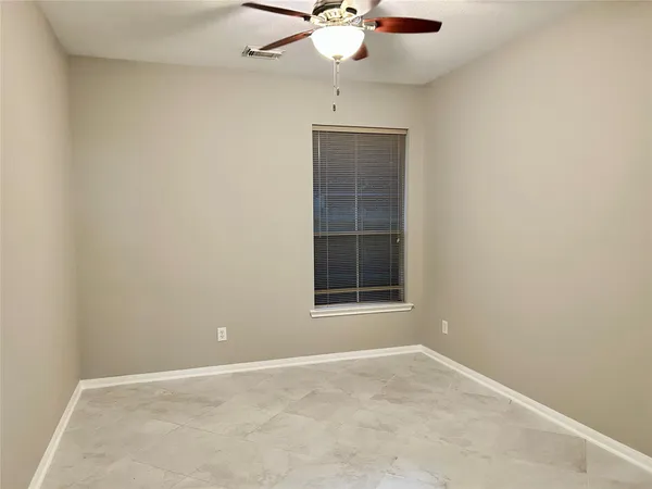 an empty room with a chandelier fan and windows