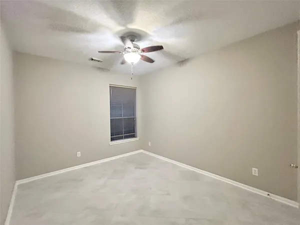 an empty room with a window and a fan