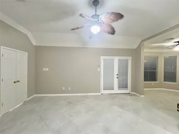 a view of an empty room with chandelier fan