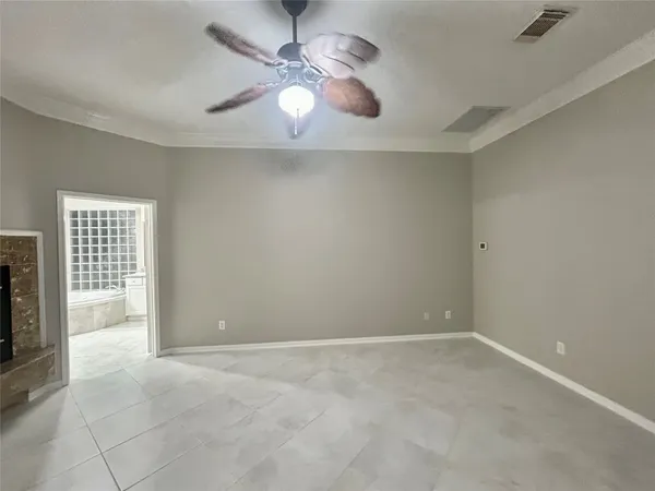 an empty room with chandelier fan and windows