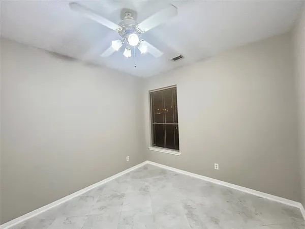 an empty room with a chandelier fan and windows