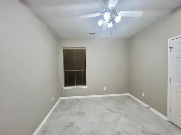 an empty room with a chandelier fan and windows