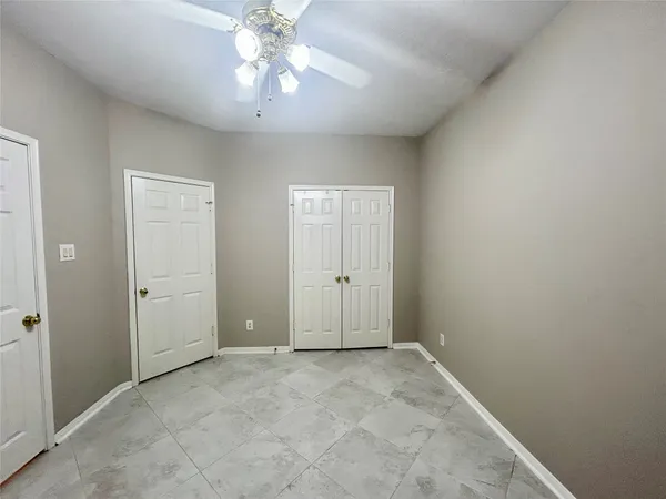 an empty room with a chandelier fan and windows