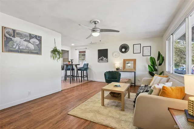 a living room with furniture a clock on wall and a window