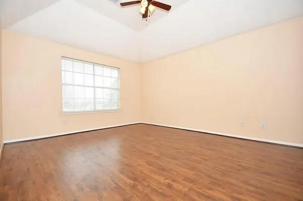 an empty room with wooden floor and windows