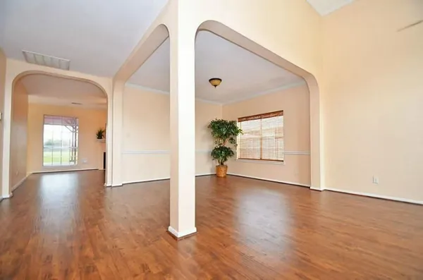 an empty room with wooden floor mirror and windows