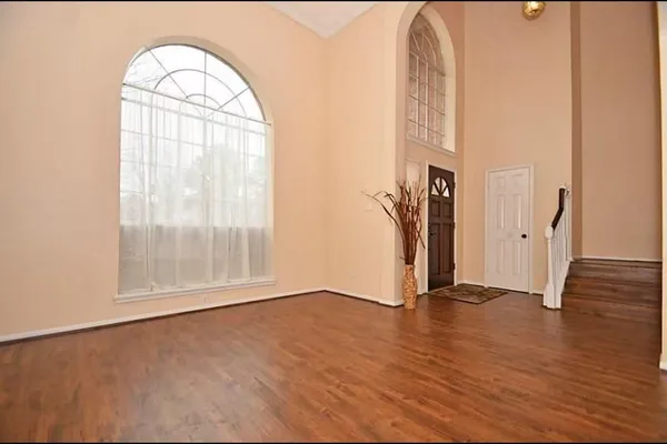 an empty room with wooden floor fireplace and windows