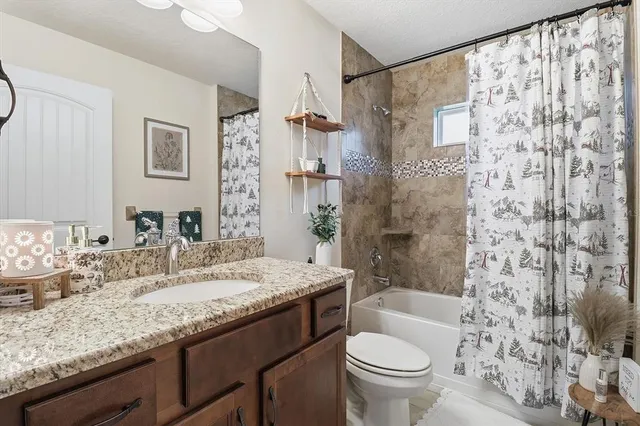 a bathroom with a granite countertop sink a toilet and shower