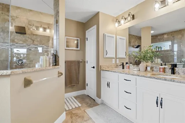 a bathroom with a granite countertop sink mirror and shower