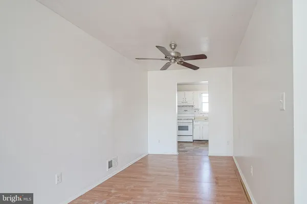 a view of a hallway with wooden floor and a ceiling fan