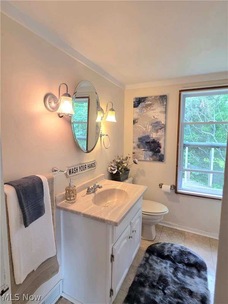 398 North Chillicothe Road Aurora, OH 44202 - Photo 17 of 39 Bathroom featuring a single vanity with a solid surface countertop, an oval mirror, and a two-light sconce