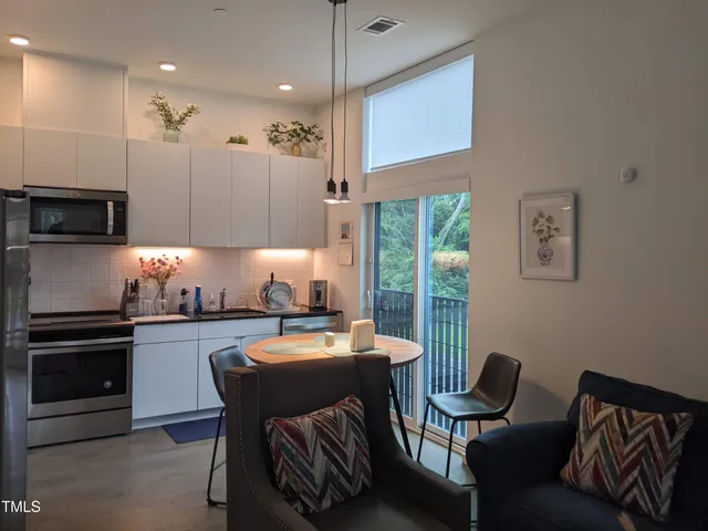 a kitchen with stainless steel appliances granite countertop a sink a stove a refrigerator a microwave oven with a dining table and chairs