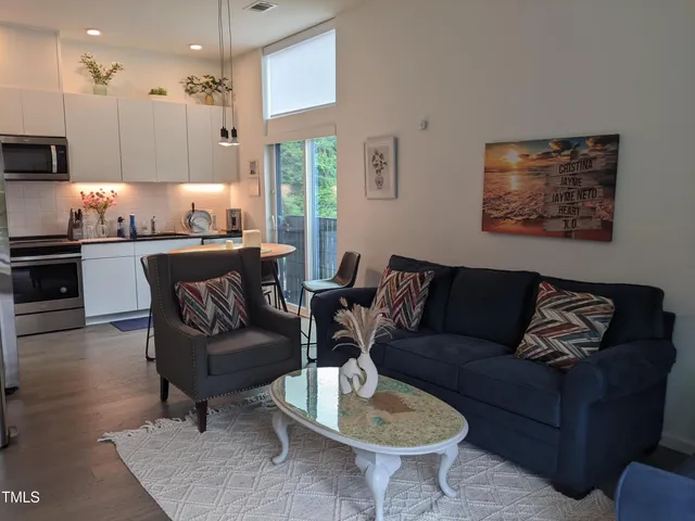 a living room with furniture kitchen view and a chandelier