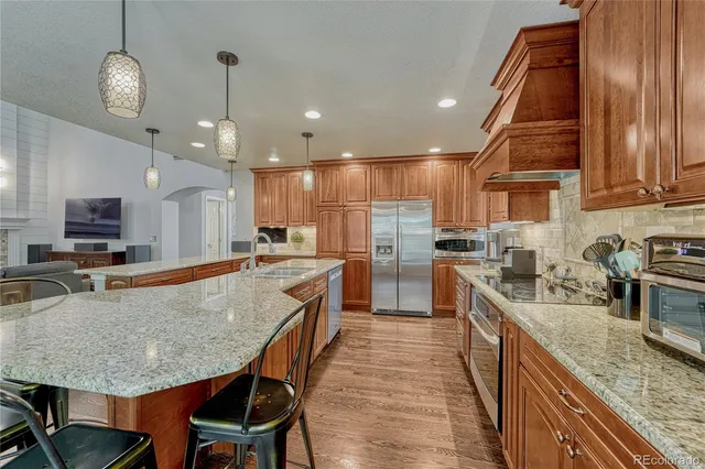 a large kitchen with stainless steel appliances granite countertop a stove refrigerator and a sink