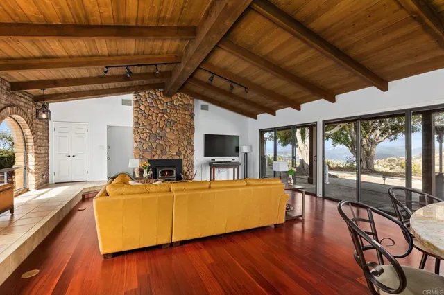 a living room with furniture floor to ceiling window and wooden floor