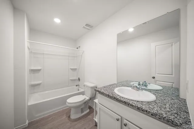 a bathroom with a granite countertop sink mirror toilet and bathtub